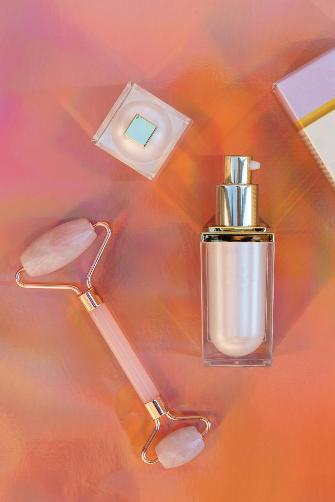 Luxury skincare product display with a rose quartz roller in a studio setting.
